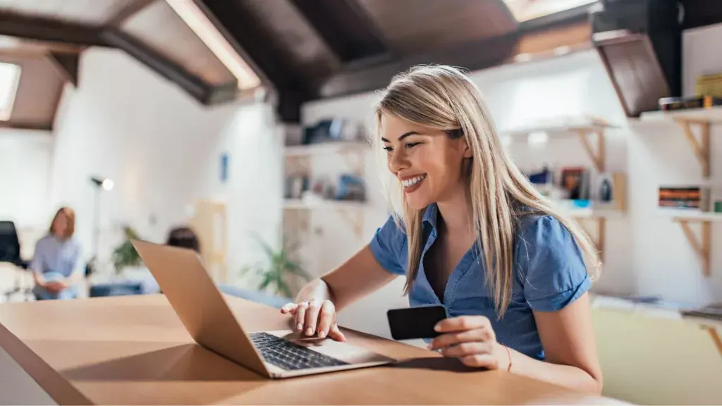 Woman on a laptop holding a bank card, making an eCommerce payment